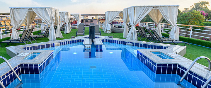 Das Sonnendeck der MS Nile Excellence bietet ein modernes Ambiente mit komfortablen Liegen und einem Pool. Der Nil zieht ruhig an Bord vorbei.